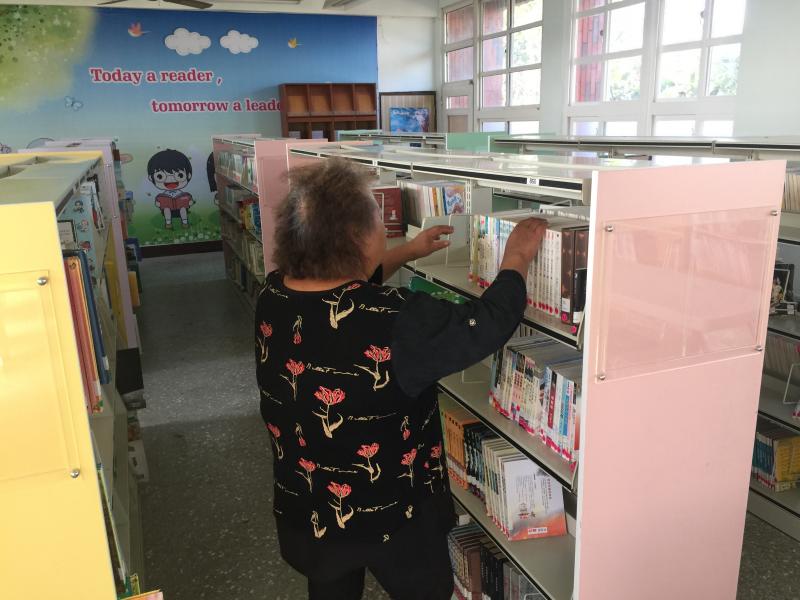 阿嬤在找尋自己需要的書籍