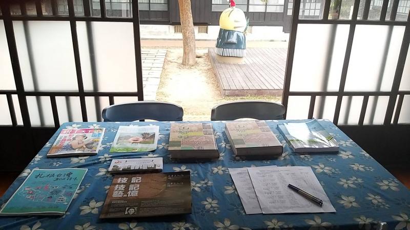 日式建築內部的桌面，擺放著各樣書籍，總是吸引著遊客翻閱，尤其是上方的90週年校友紀念冊。