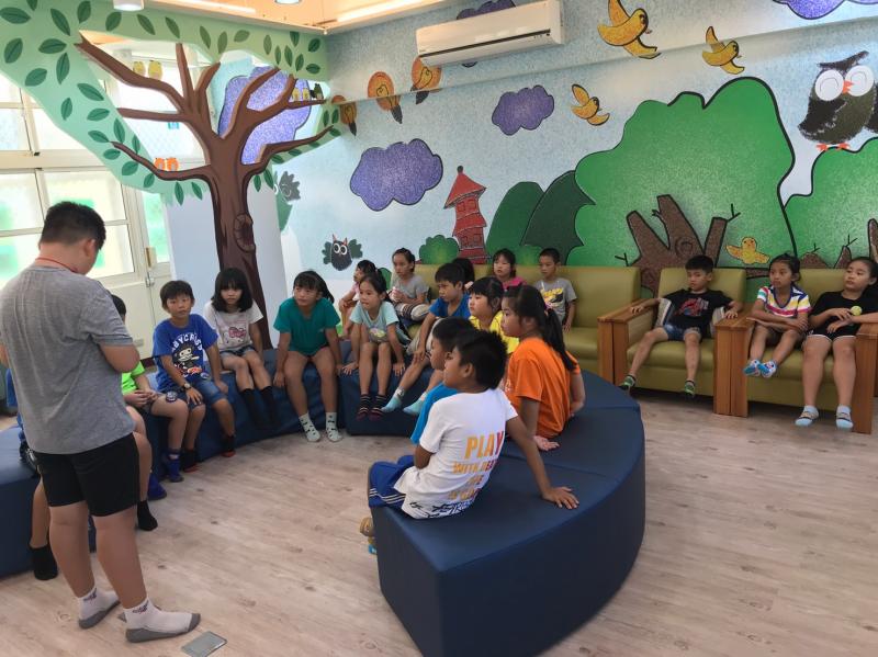 大哥哥很認真地講故事給學校的弟弟妹妹們聽