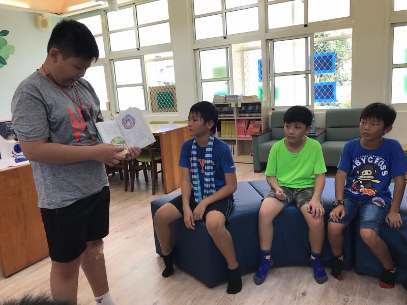 大哥哥很認真地講故事給學校的弟弟妹妹們聽