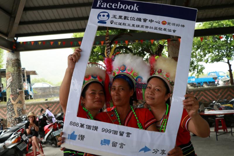 社區民眾汆著阿美族傳統服飾帶著Facebook的打卡看板拍照