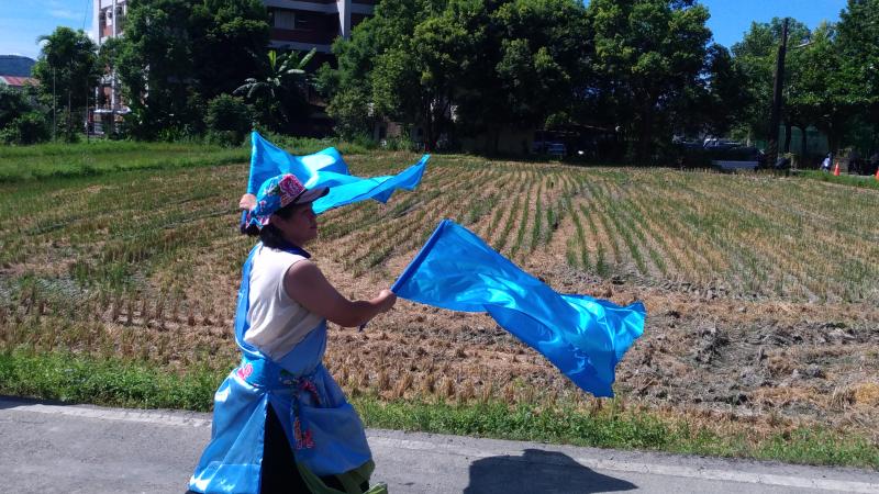 阿姨雙手揮舞著藍色大旗
