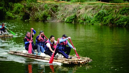 年輕人在阿美族的傳統竹筏上賣力地滑動船槳，後方鍵起大浪的水花，遠超過其他的船隻。