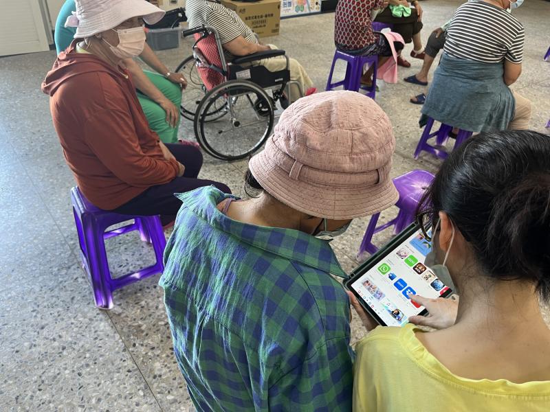 教導老年婦女使用平板電腦及下載APP。此活動透過提高數位素養,幫助老年人更好地管理健康。