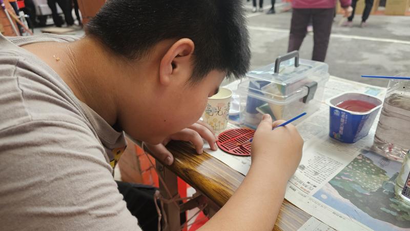 大人們忙著仔細聽摸彩名單，小朋友彩繪雷雕杯墊。