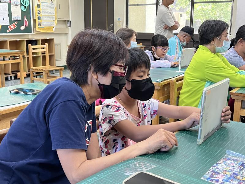 小女童與奶奶一起專注的看著平板上的問答題，認真思考、共同解題