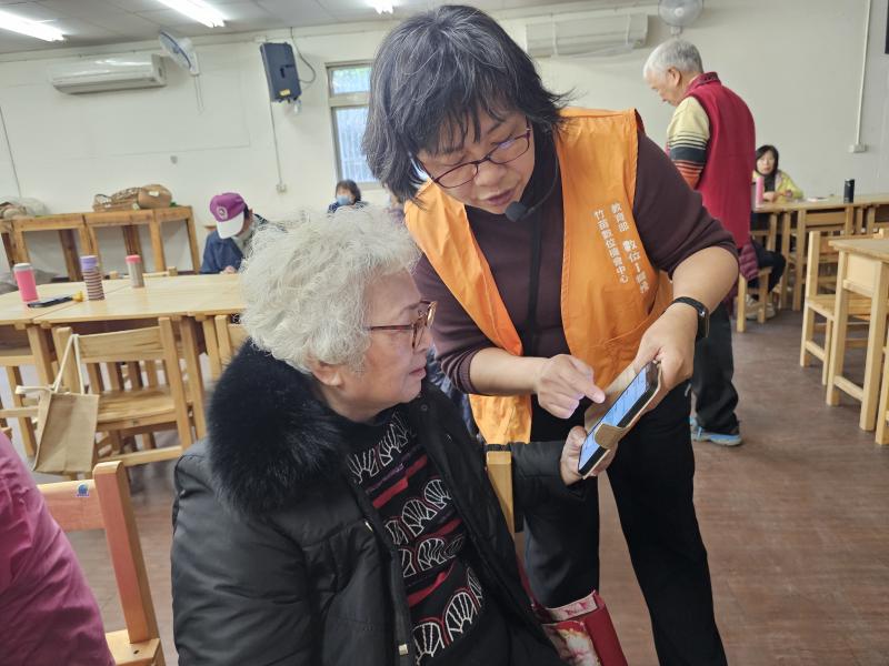 芎林DOC執行秘書正在教長者設定智慧型手機。