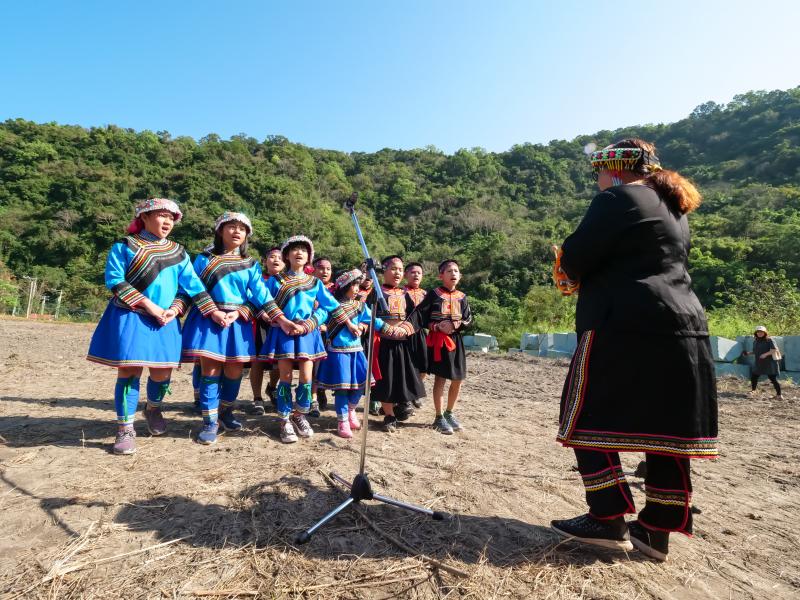 年輕的布農男孩女孩穿著傳統服裝，左手牽左手。右手牽右手，為播種記唱起「Maqasmav Kuzakuza 認真工作」的歌。