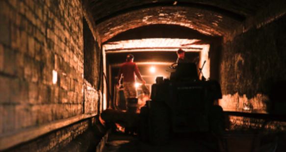 日豐磚窯廠的隧道窯，前方的入口處露出細小的燈光，老闆在陰暗悶熱的環境下進行燒磚的工作。