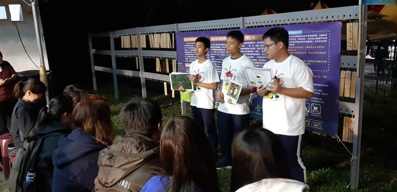 志工解說員排排站在營或重的介紹海報前，為前來聆聽的遊客介紹解釋螢火蟲的習性與細節。