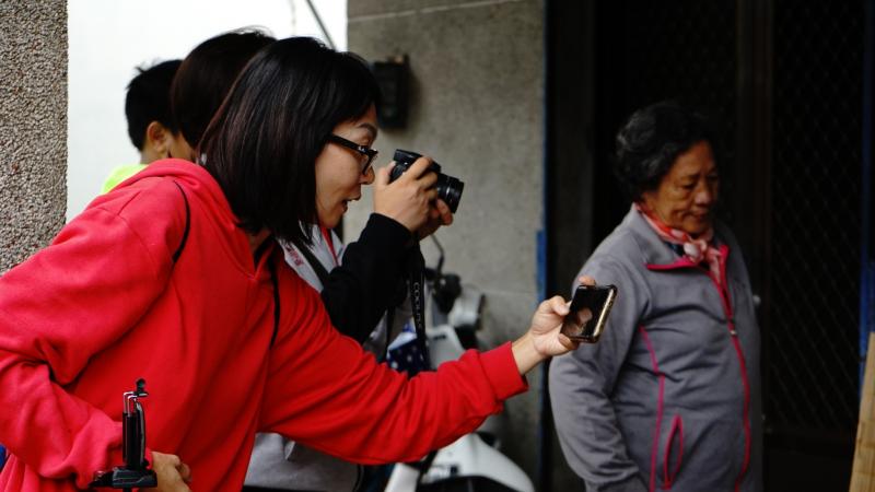 學員以左手拿著手機，專注的在作影像的拍攝，作為學習課程影像後製的素材。