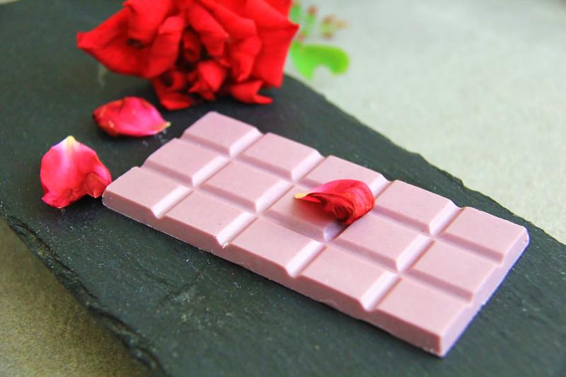 產品照片，淡粉色的白巧克力，點綴上鮮紅色的花瓣