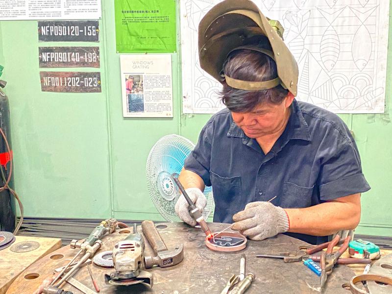 凃正南老闆正在用氬焊將鐵條朔型,準備製作山型作品。