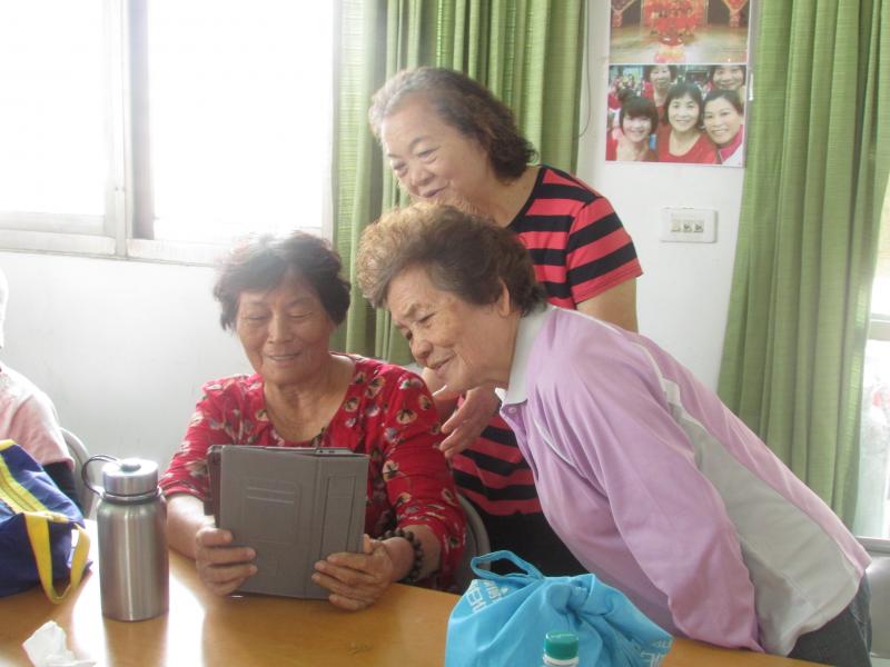 3位學員聚在一起玩拍照及攝影，看到顯示在上面的自己覺得很新奇，不自覺笑的樂呵呵。