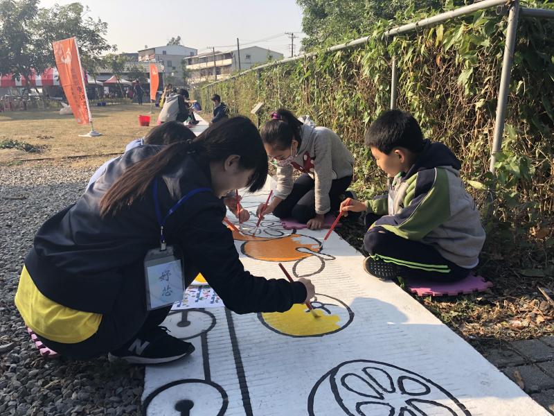資訊志工及學生一起合作彩繪步道的情景