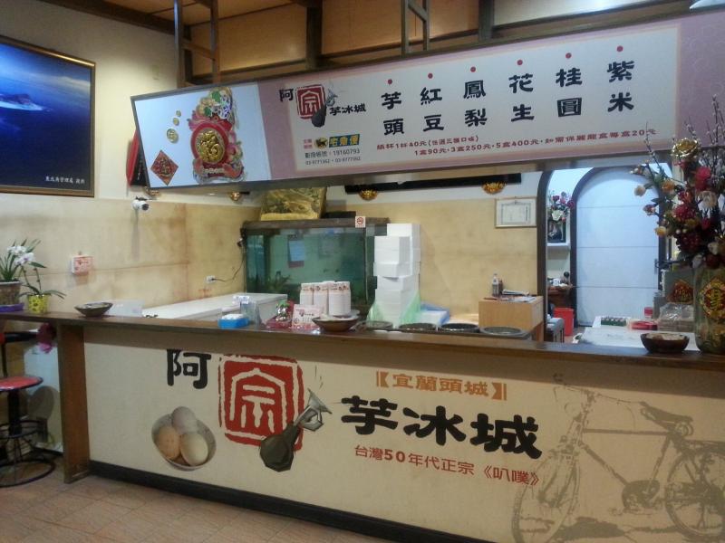 阿宗芋冰城吧檯下方寫著台灣五零年代正宗吧噗，上方看板陳列紫米、桂圓、花生、鳳梨、紅豆、芋頭六種口味。