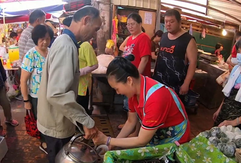 黎先生在新埔第一市場對攤販奉茶的情形