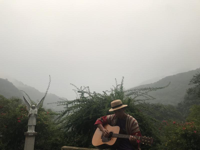 清泉咖啡小老闆在細雨中彈唱吉他。