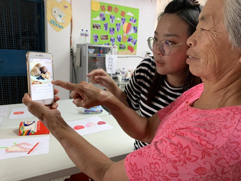 <p>八十幾歲的阿嬤為了找到＂大蒜＂的樣子，認真地聽老師說如何用手機查詢圖片。</p>