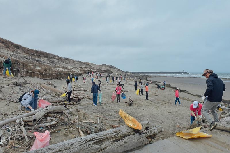 淨灘人潮散落在海灘上，專注撿拾無法被大自然分解的各種海洋廢棄物。