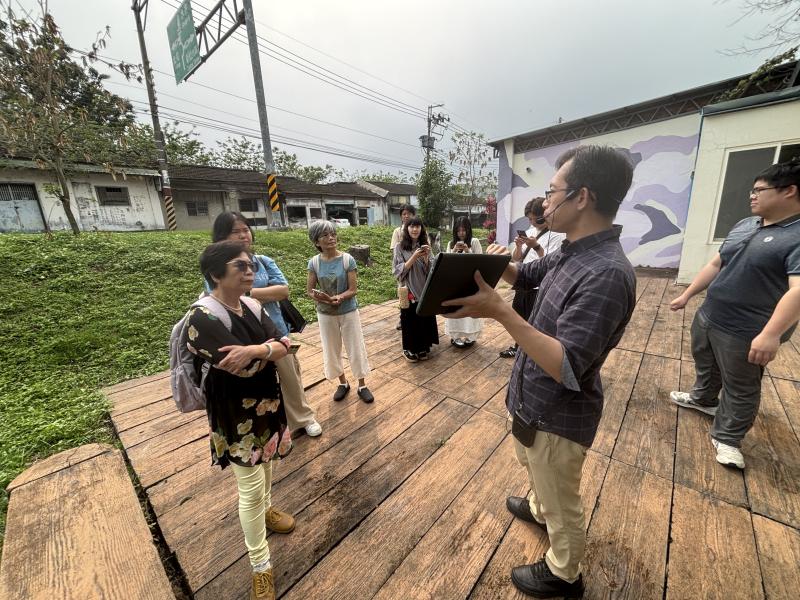 <p>講師手持平板等數位工具，於新社景點現地進行解說，結合走讀方式帶領民眾深入認識在地文化與環境特色。透過即時圖像、資料展示與生動說明，引導學員觀察新社各景點的歷史脈絡與地方故事，並透過提問與互動交流，提升參與感與學習興趣。在輕鬆的戶外教學氛圍中，民眾不僅能了解新社的特色景點，也能實際運用數位工具進行記錄與分享，進一步強化對地方文化的認識與連結。</p>