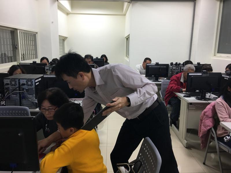 老師對著學員講解如何操作平板電腦