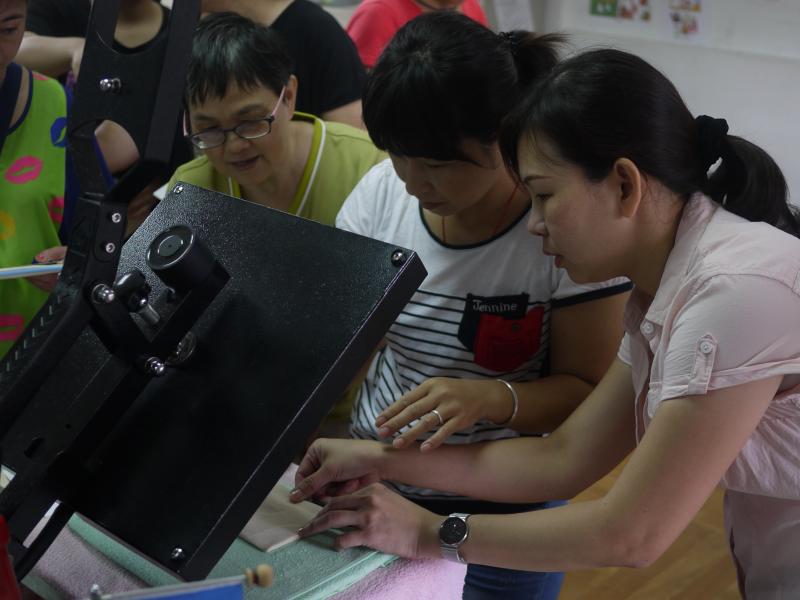 講師指導學員操作熱轉印機台   進行創意布包熱轉印