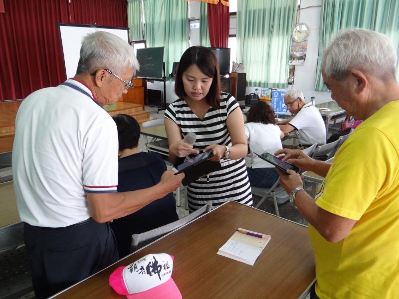 網路菜市場課程進行中，學員不懂比價APP操作，講師一旁指導。