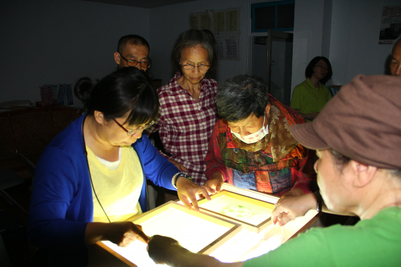 在昏暗的環境，講師指導學員們如何使用感光台製作絹版