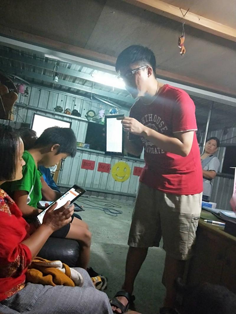 講師在小朋友面前舉起平板，說明app的使用方式。