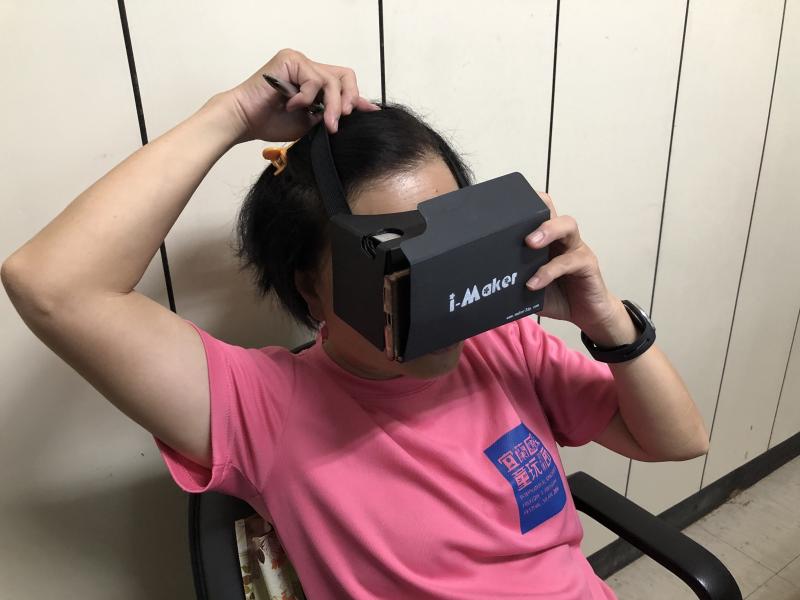 阿嬤將VR眼罩帶上體驗設備
