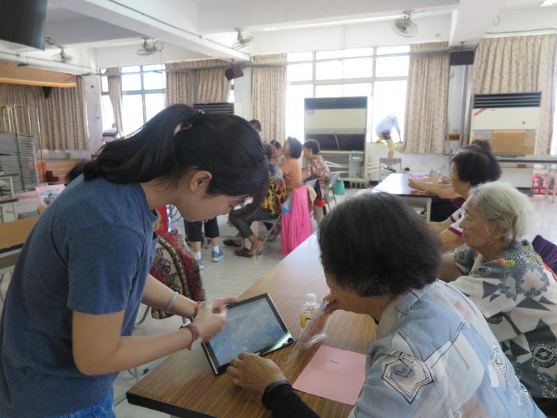 志工協助長輩操作平板。