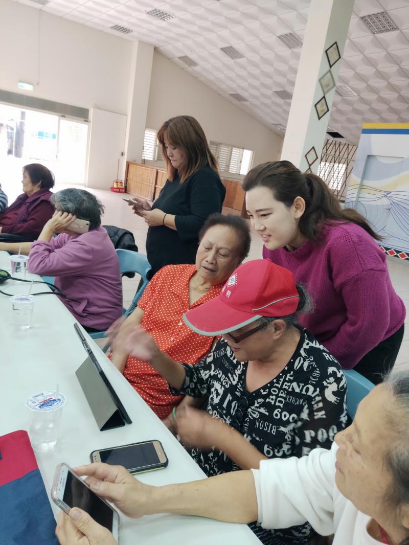 文化健康站的服務員協助長輩使用平板電腦，為他們說明並且解決問題。