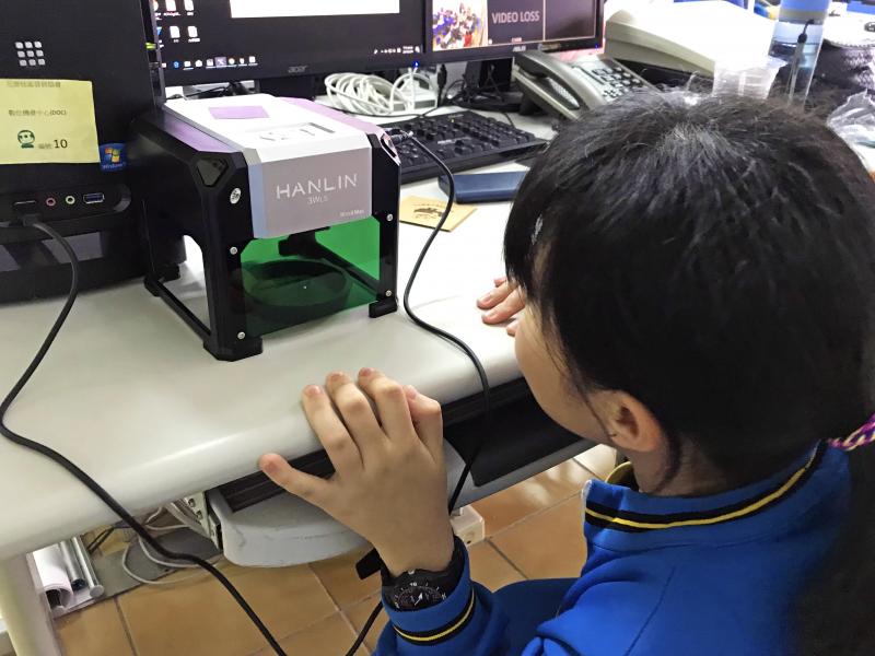 好奇看著雷雕機運作的學員。