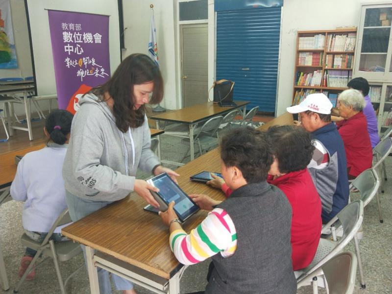 講師以雙手幫助長輩正確的使用平板，協助使用應用程式。