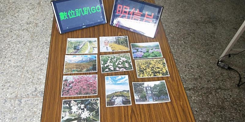 將學員製作的成品明信片整齊的擺在桌上，並且運用字報跑馬燈app寫出，課程名稱數位趴趴GO與明信片的字樣。