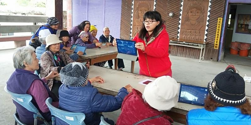 講師以雙手將平板放在學員面前示範，如何開啟視訊鏡頭，平板上顯示出其中一位學員的臉部。