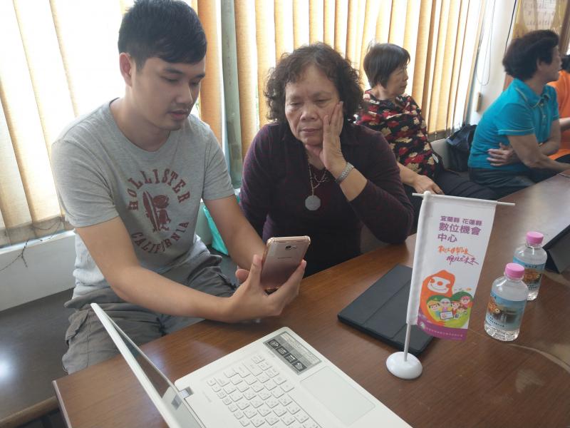 年輕學員在旁邊以手機與長輩交流應用程式的使用方式。