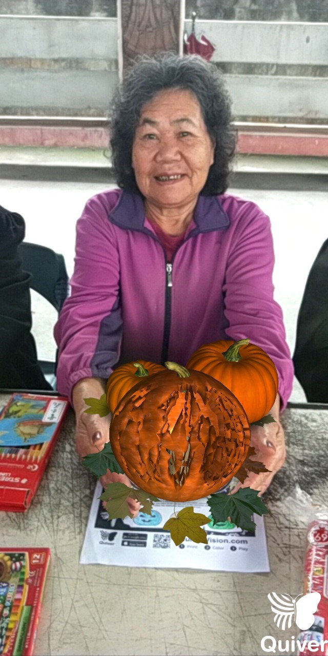 在圖紙塗上顏色後，用AR的程式將2D平面的南瓜以3D立體投影出，相事長輩將南瓜以雙手捧著。