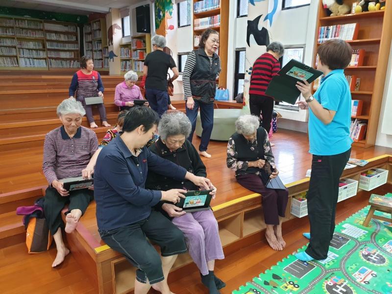 在一個充滿書香的空間裡，年長的長輩學員們各自拿著一台平板，由講師引導使用健康雲app。