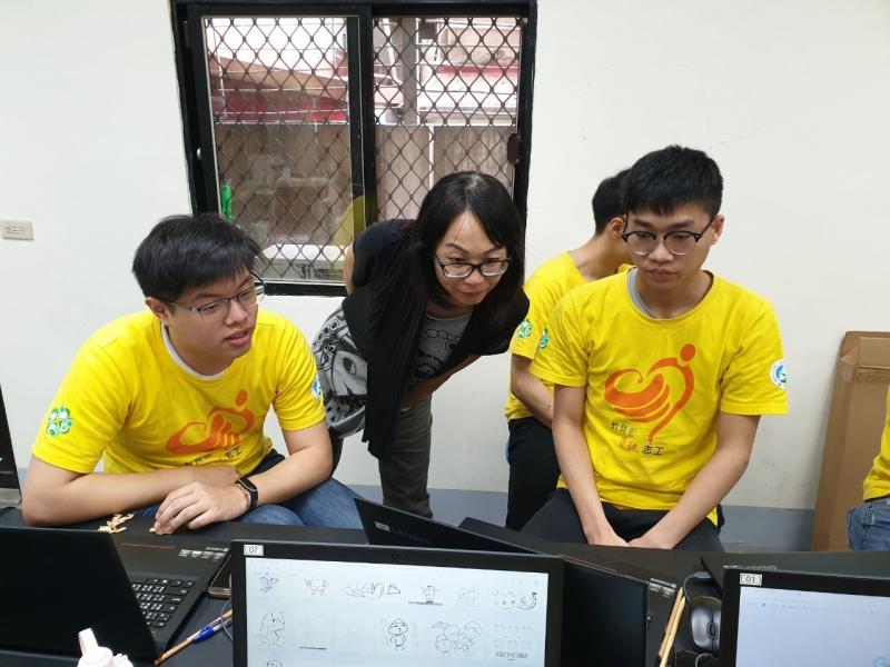 講師走到兩個志工之間查看他們的電腦。