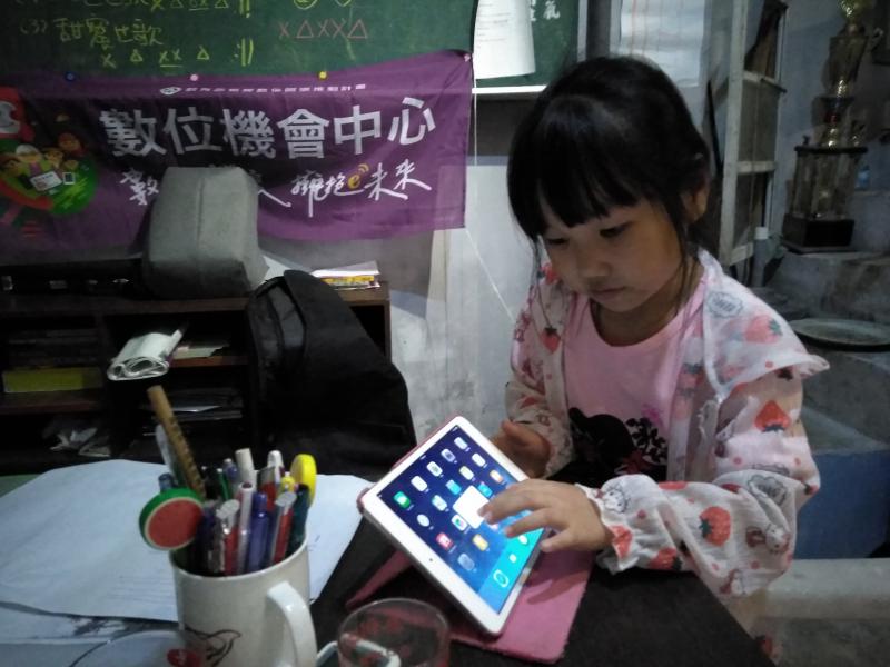 一位年幼的學員正觸碰平板的螢幕，嘗試探索未知的機器。