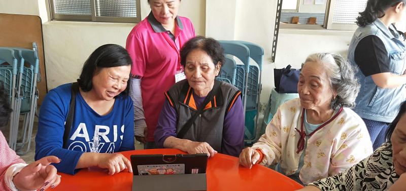 一位學員與其他兩位長輩分享自己找到的影片，三個人就一同觀看平板電腦。