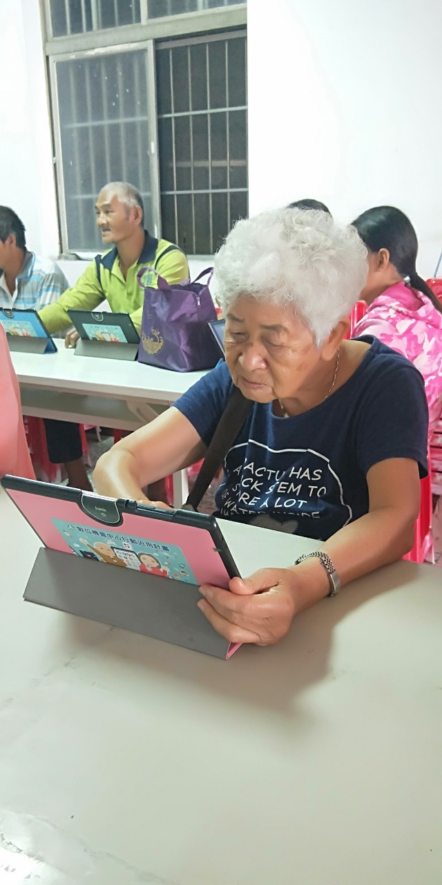 阿嬤努力且專心的在螢幕上滑滑點點，學習基礎的平板操作以及google雲端硬碟的使用。