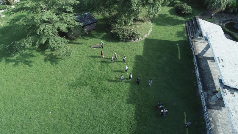 架駛空拍機從高空視角向下拍攝，一米七的人小如米粒如在草地上的一般。