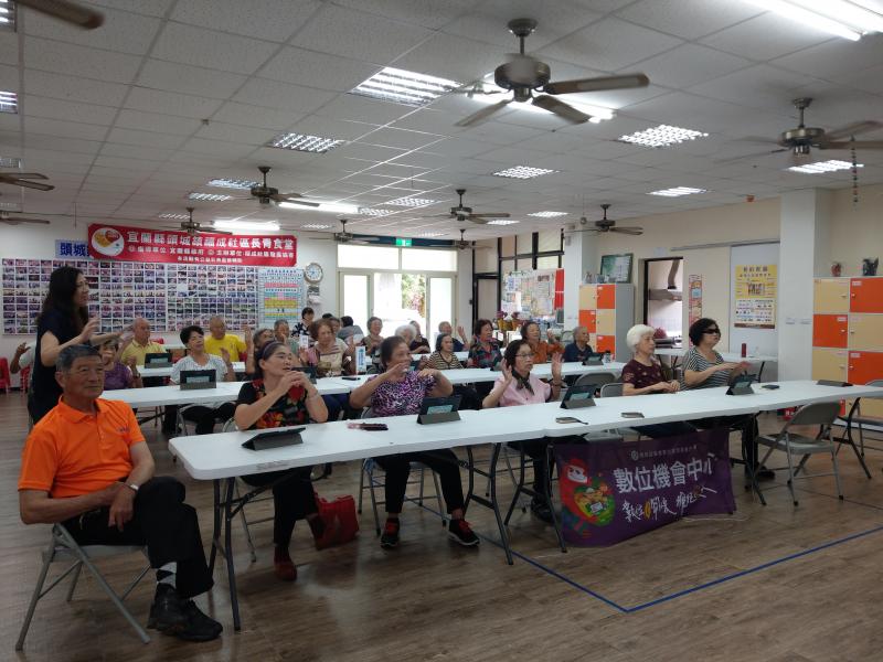 講師位於教室左方說明課程內容，學員面對前方在講師指導下，將雙手平舉於面前。