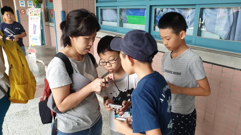 較為年長的學員正在嘗試教導小學員們相機的使用方式，並且分享所拍攝的照片。