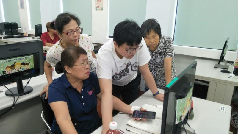 三位學員坐在電腦桌前，講師傾斜身體操作滑鼠，幫助學員使用電腦上的排解問題。