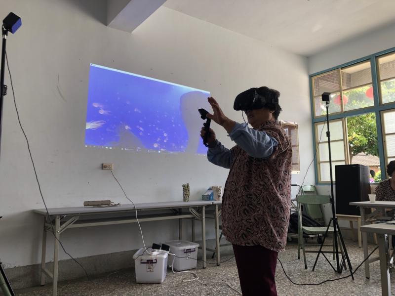 學員阿嬤很勇敢的自告奮勇說要體驗，看到精彩處還會不由自主的伸出雙手來跟VR世界裡魚兒互動
