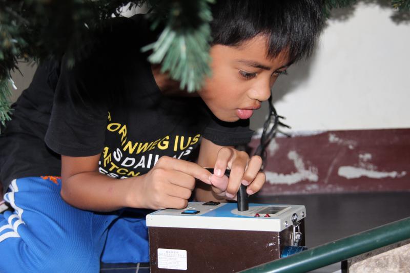 學員拿著輻射偵測器材於DOC教室環境偵測輻射值，學員連石頭都不放過，正在進行石頭輻射值測試。